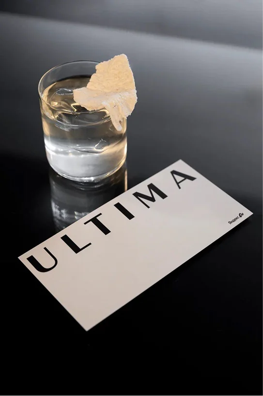 Ultima card next to a glass